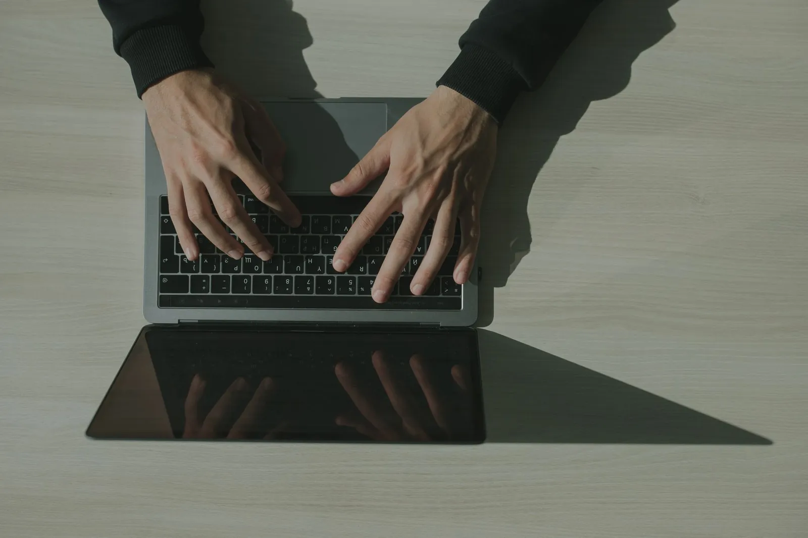 Handen typen op een laptop in een donkere werkruimte
