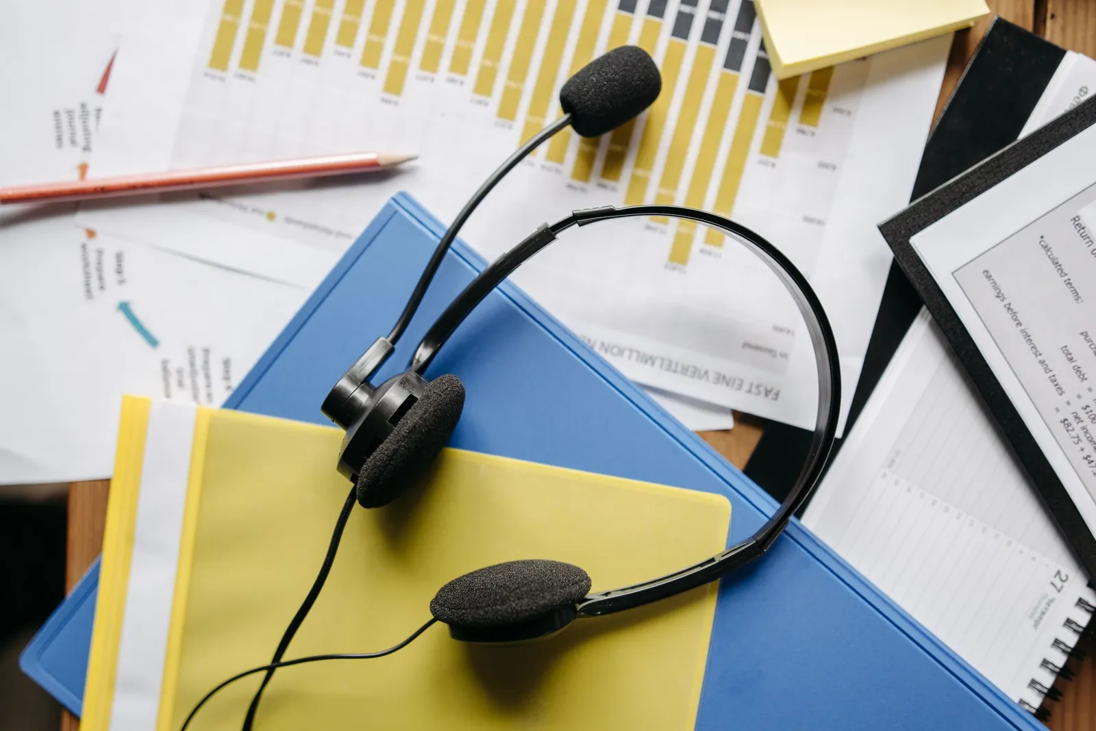 Headset op een bureau met papieren en een blauwe map