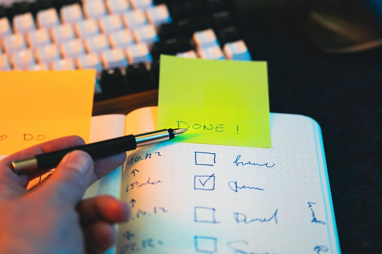Hand die met een pen vakjes afvinkt op een checklist naast een toetsenbord