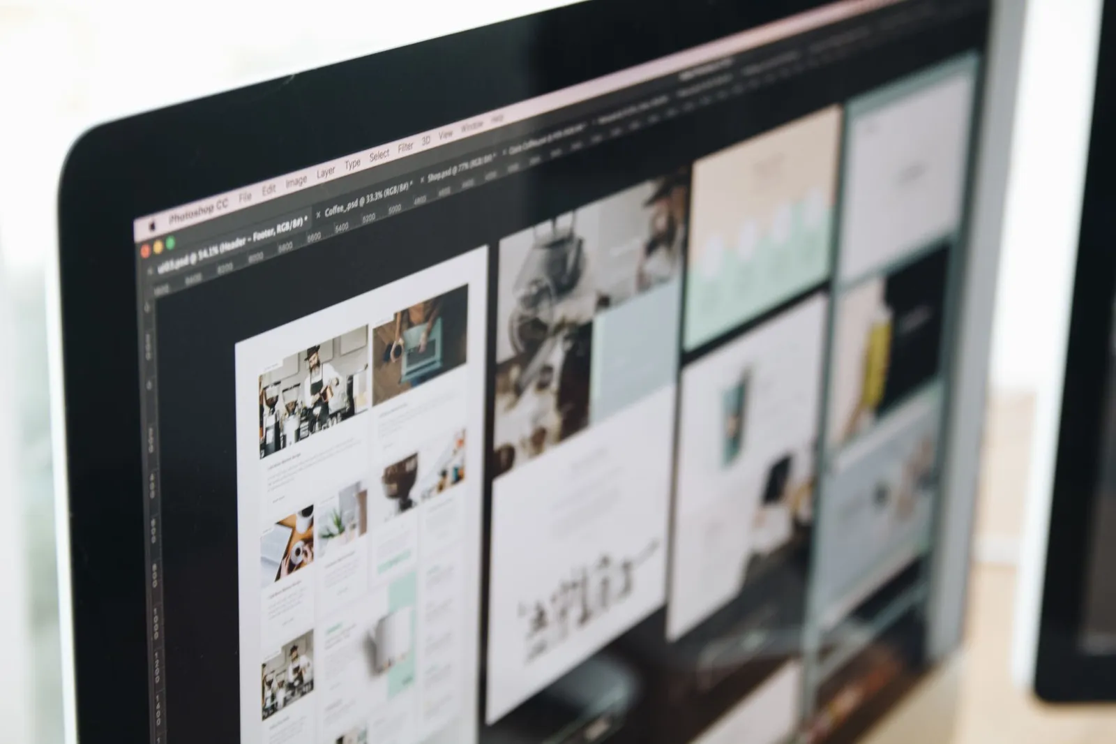 Twee beeldschermen met een websiteontwerp in een lichte werkruimte