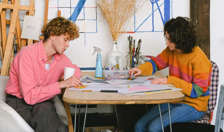 Twee mensen aan een werktafel vol schetsen en ontwerpen