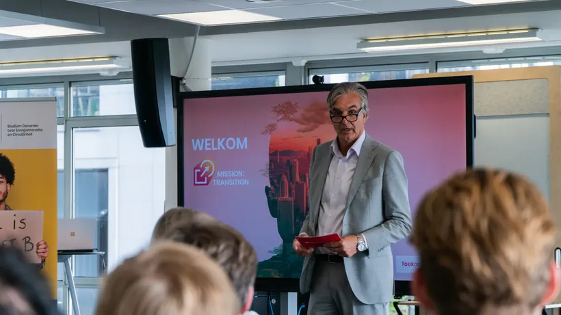 Spreker voor een groot scherm tijdens een duurzaamheidsbijeenkomst van Green Office en Hogeschool Rotterdam