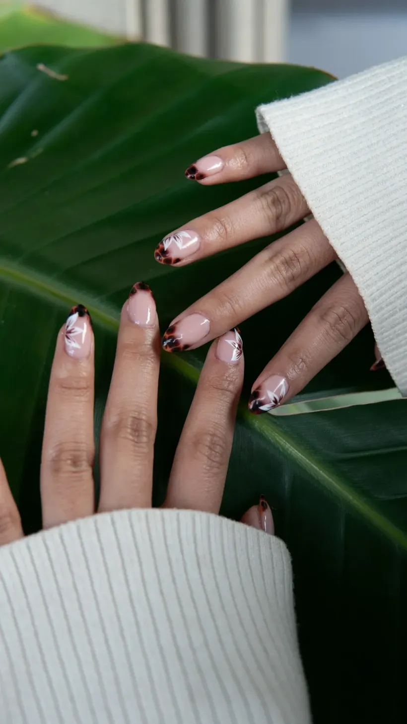 Handen met verzorgde nagels en nail art tegen een groot groen blad