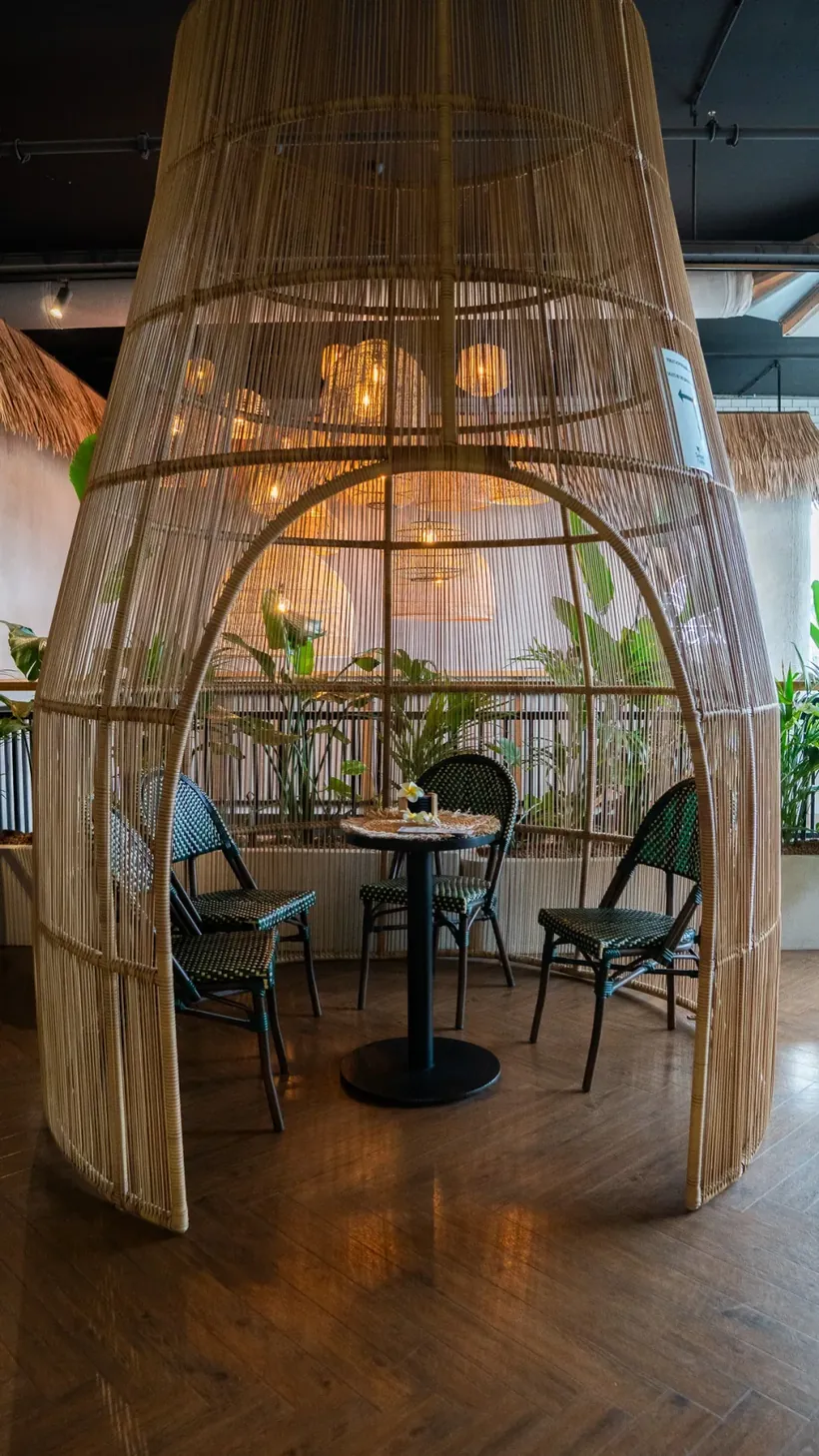 Zitje met een tafel en stoelen onder een grote rieten koepel in de salon van Indochine