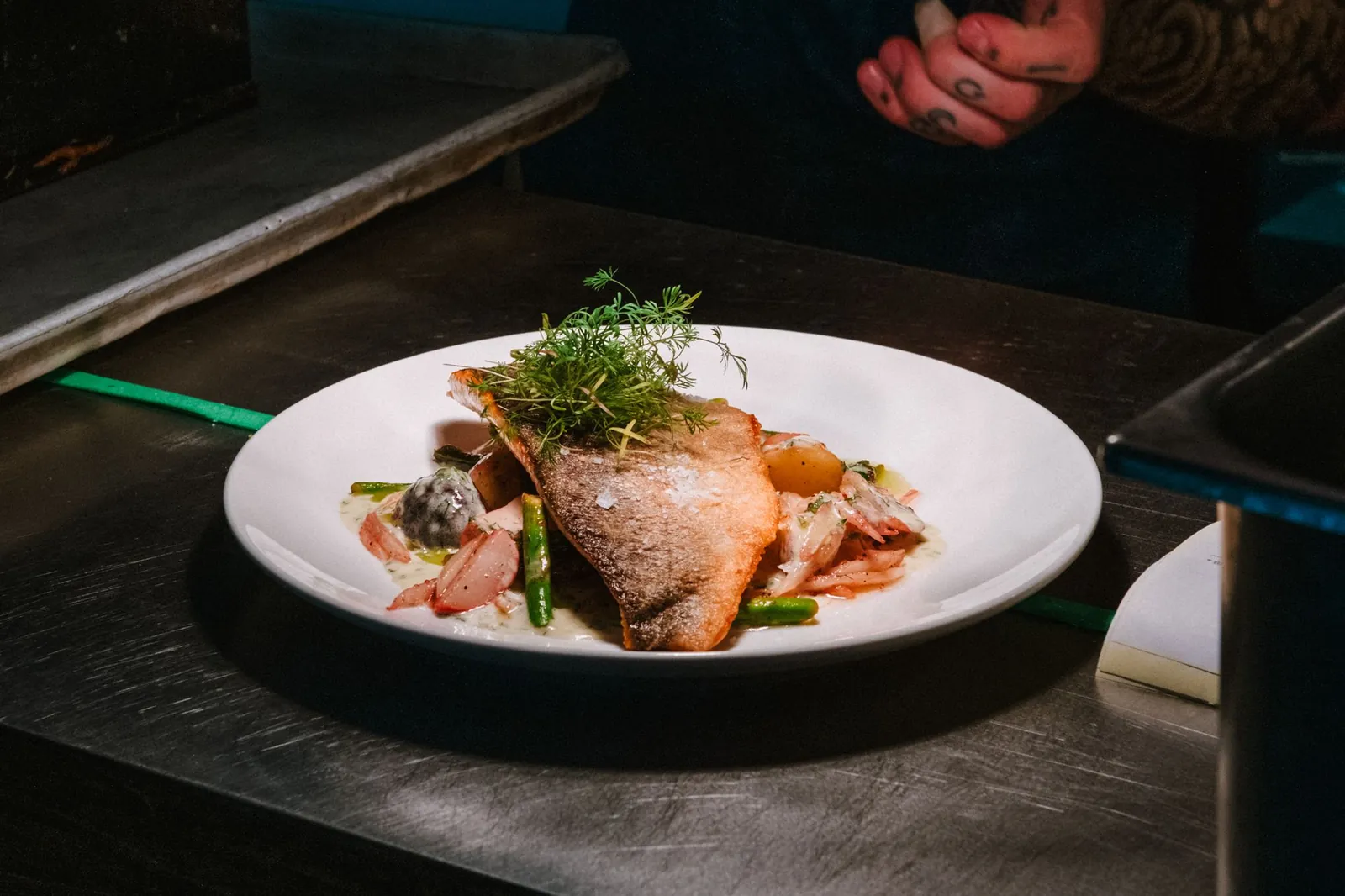 Opgemaakt gerecht op een donker bord in een restaurantkeuken