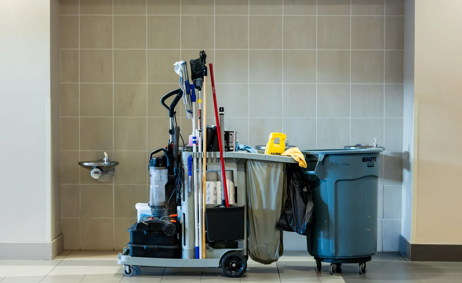 Schoonmaakkar met emmers en middelen in een gang