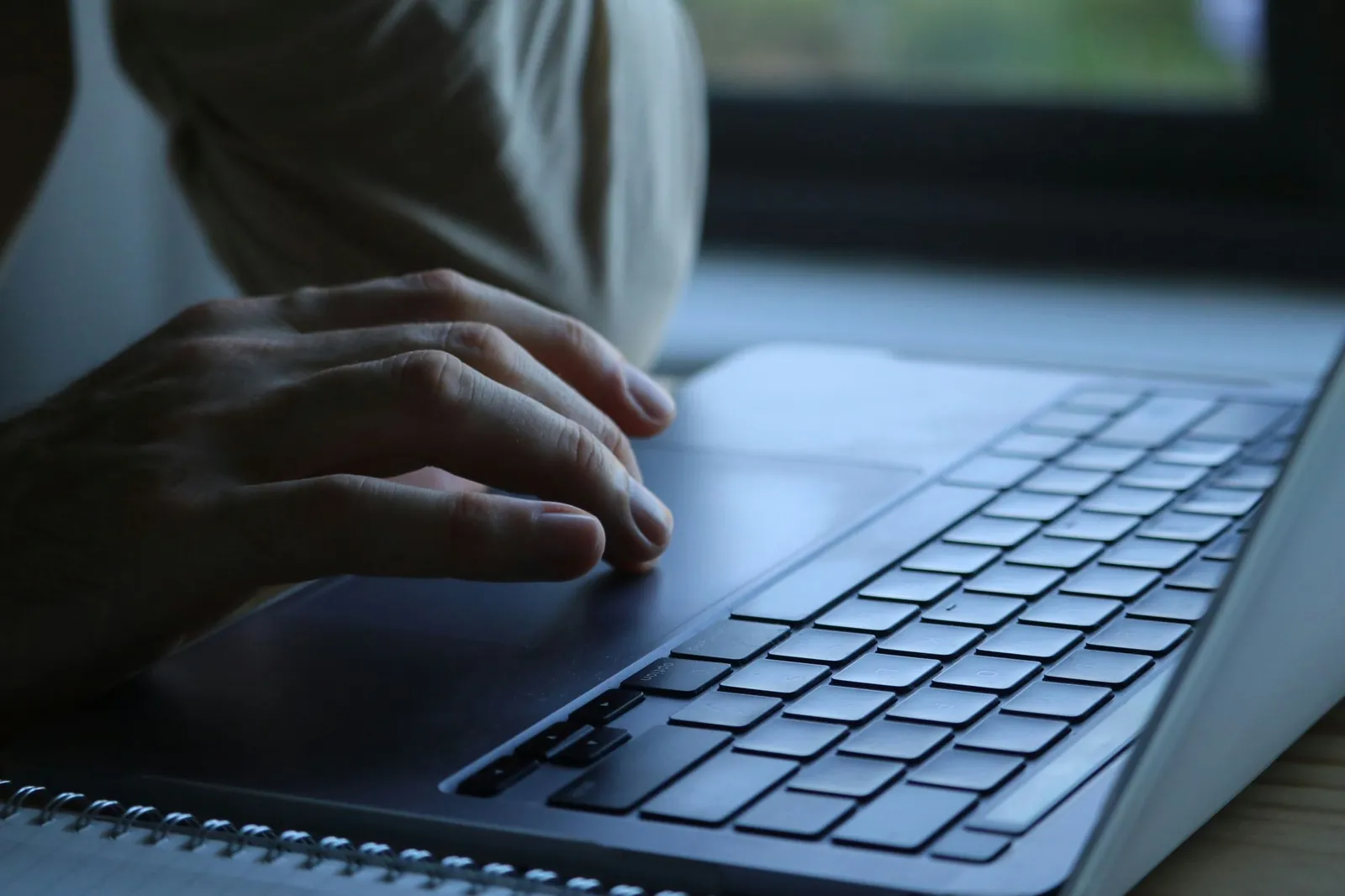 Handen typen op een laptop in een donkere omgeving