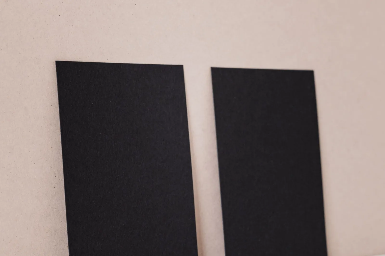 Twee zwarte visitekaartjes tegen een lichte wand