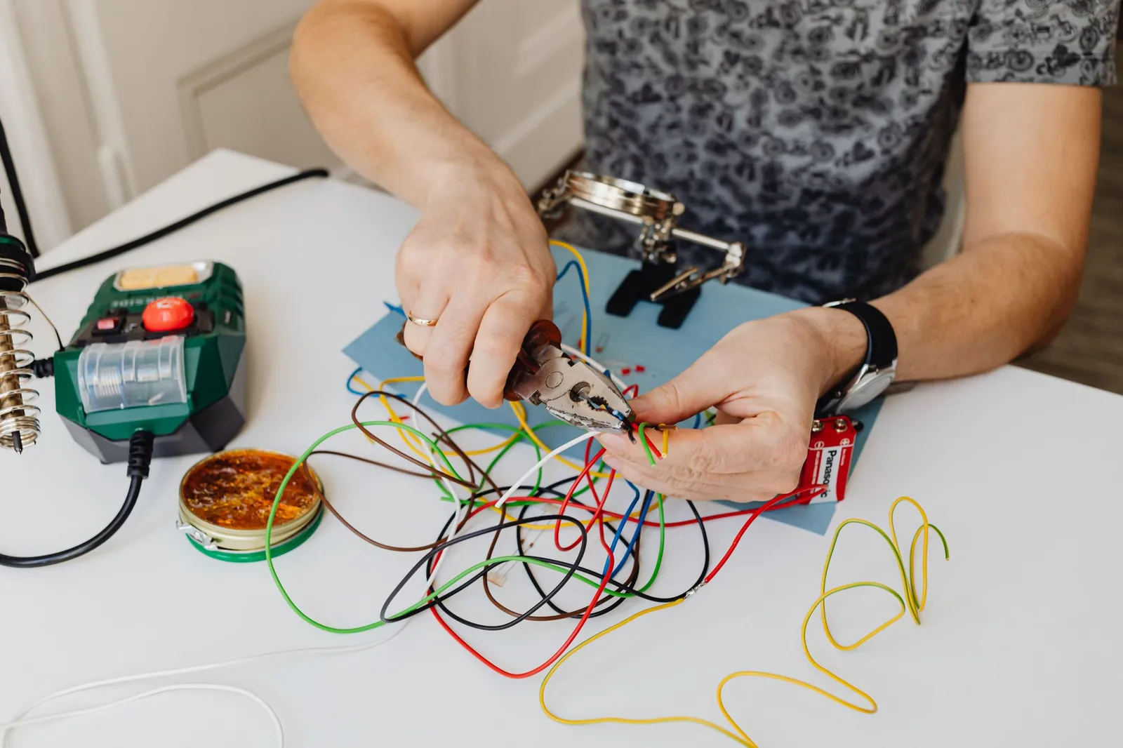 Handen knippen en strippen gekleurde elektriciteitsdraden aan een werktafel