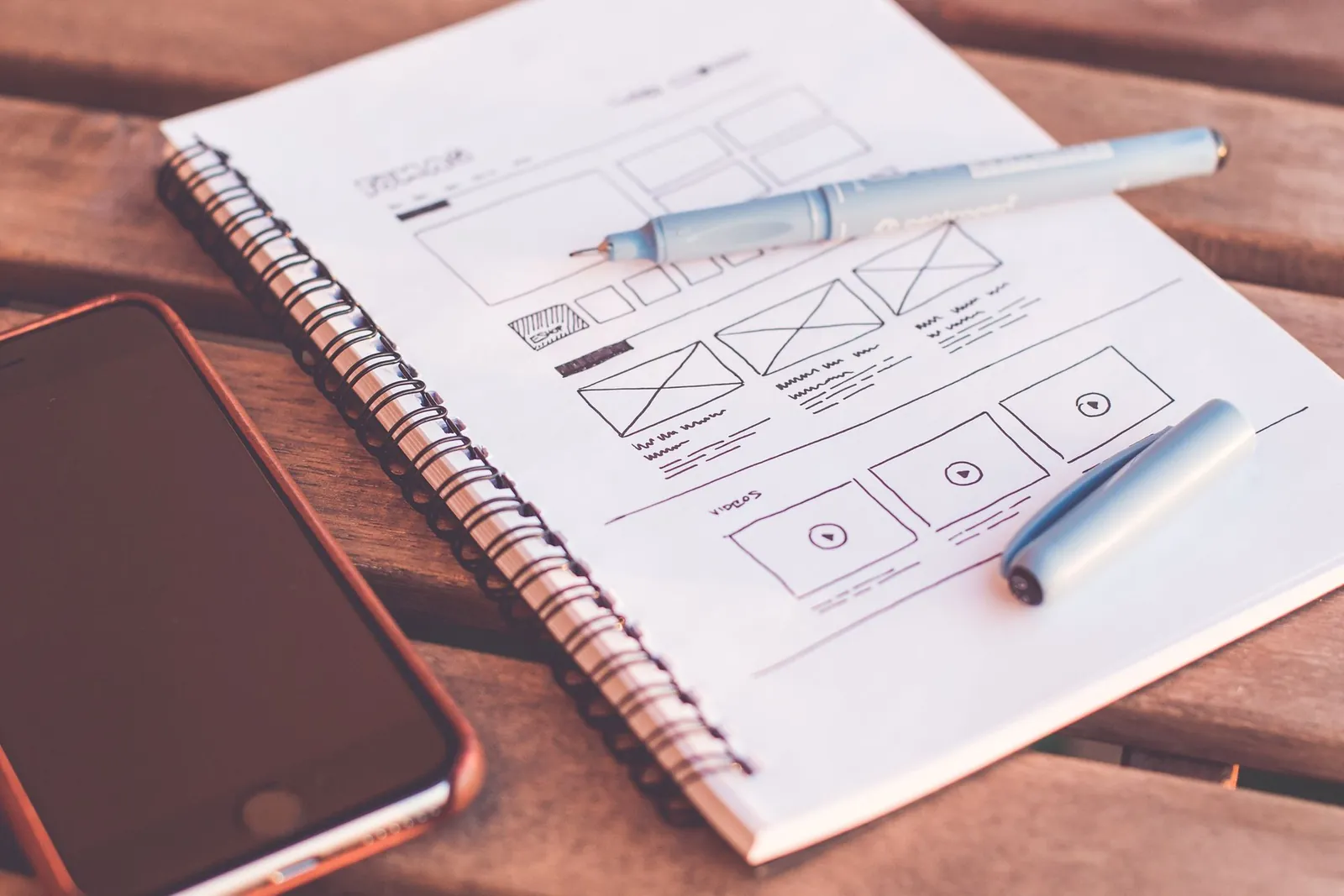 Schetsboek met een wireframe van een website naast een telefoon