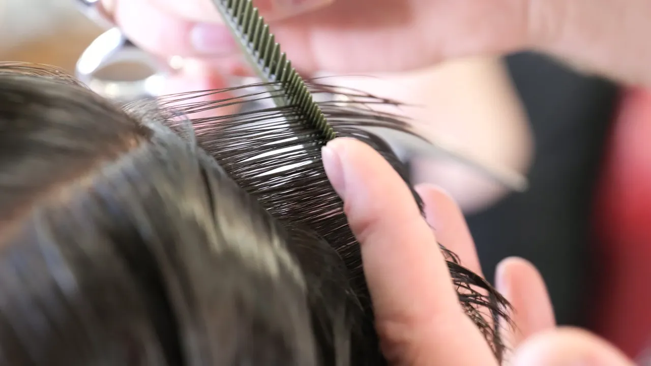 Close-up van een kapper die haar knipt, uit de openingsvideo van Ciseaux