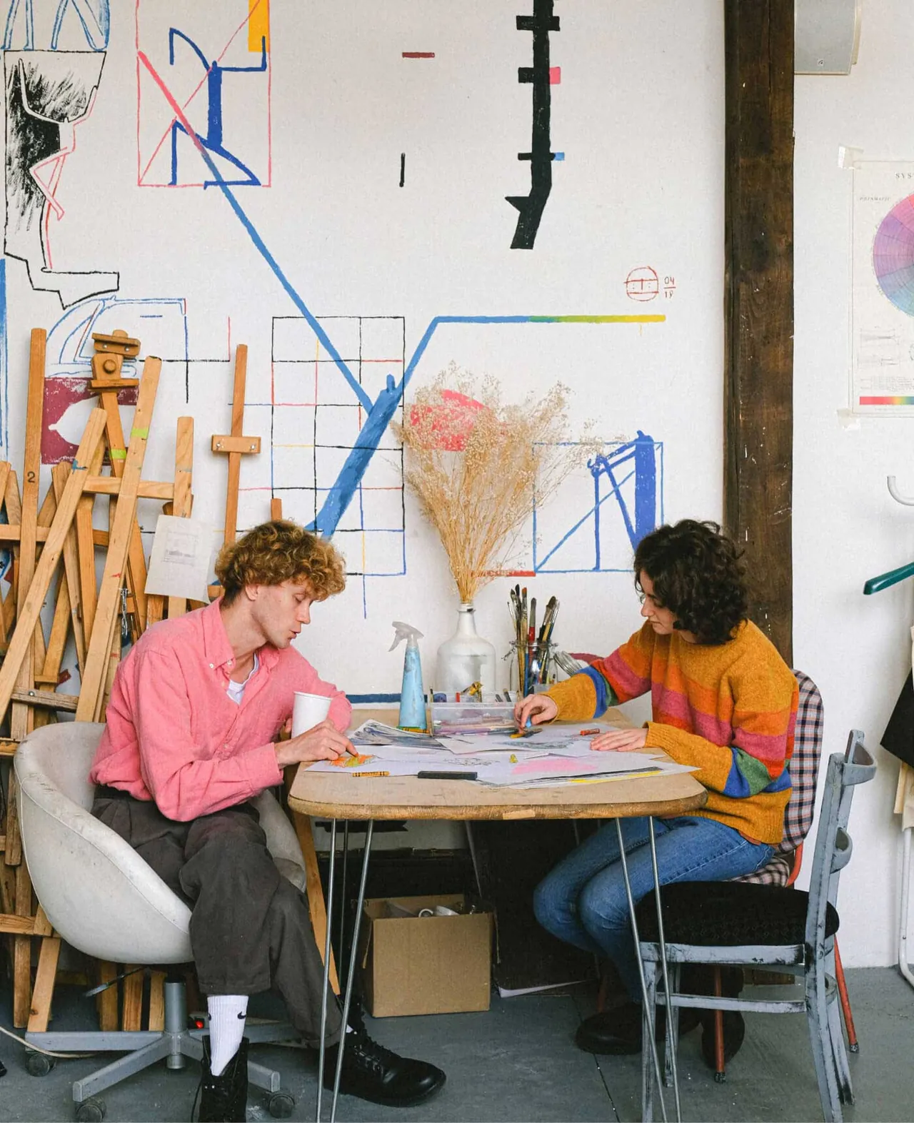 Twee mensen overleggen aan een tafel in een creatieve werkruimte