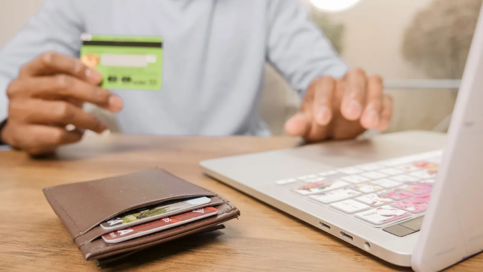 Hand met een bankpas naast een laptop tijdens het online afrekenen